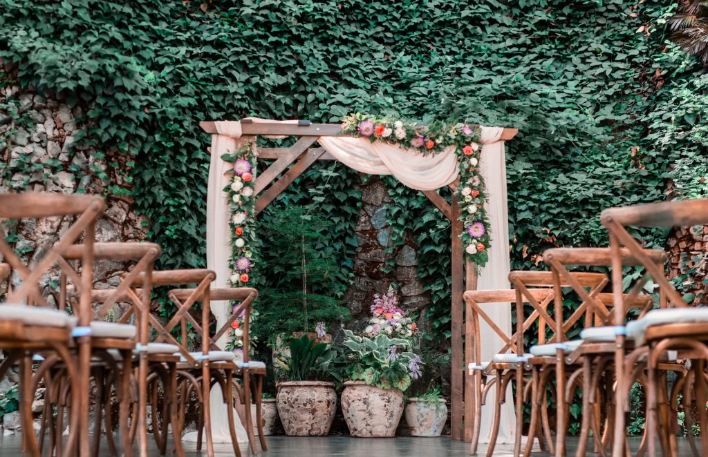 Outdoor wedding ceremony setup with floral wooden arch and ivy wall at Stone House Nevada City