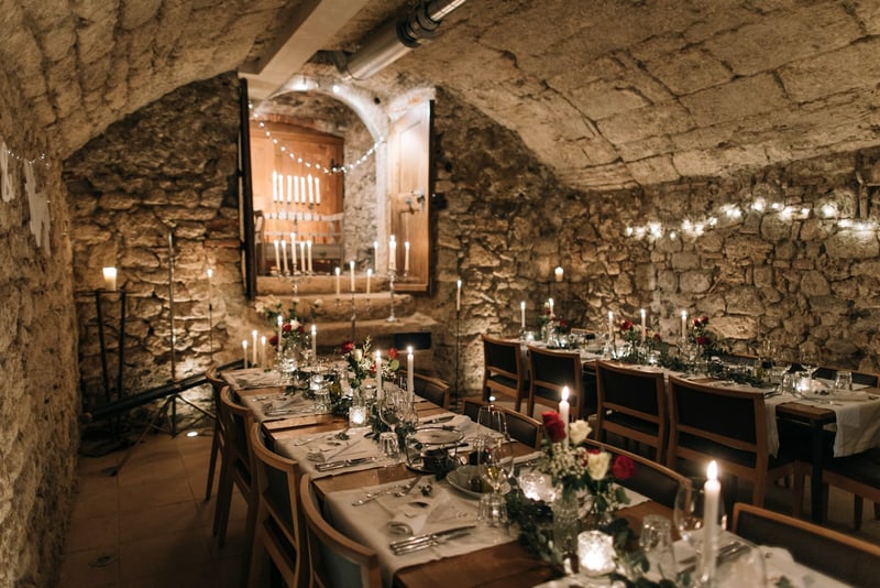 Candlelit dinner table in a historic stone-walled venue — illustrative photo for menus page