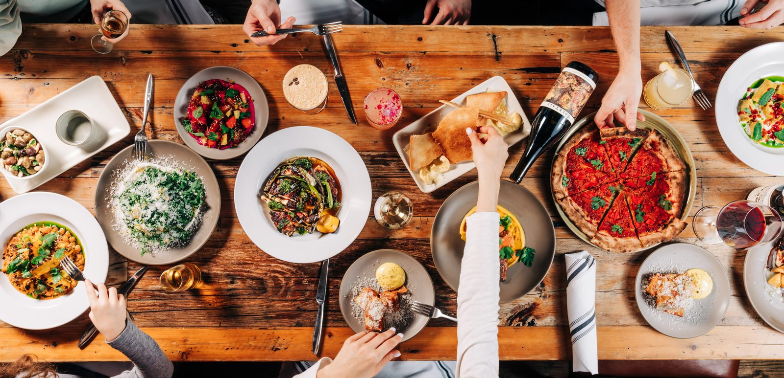 Family-style dinner at Stone House Nevada City — overhead view of wood-fired pizza, seasonal salads, and house-made pasta plated for a private celebration