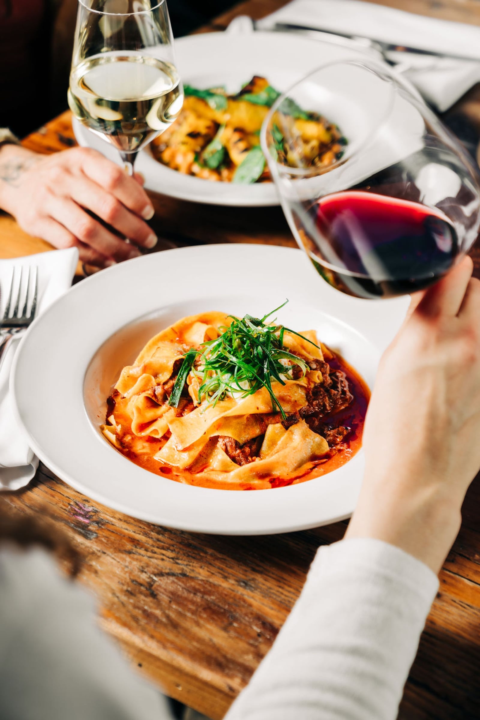 Family-style pasta service with wine pour at a Stone House Nevada City private event — chef-crafted catering
