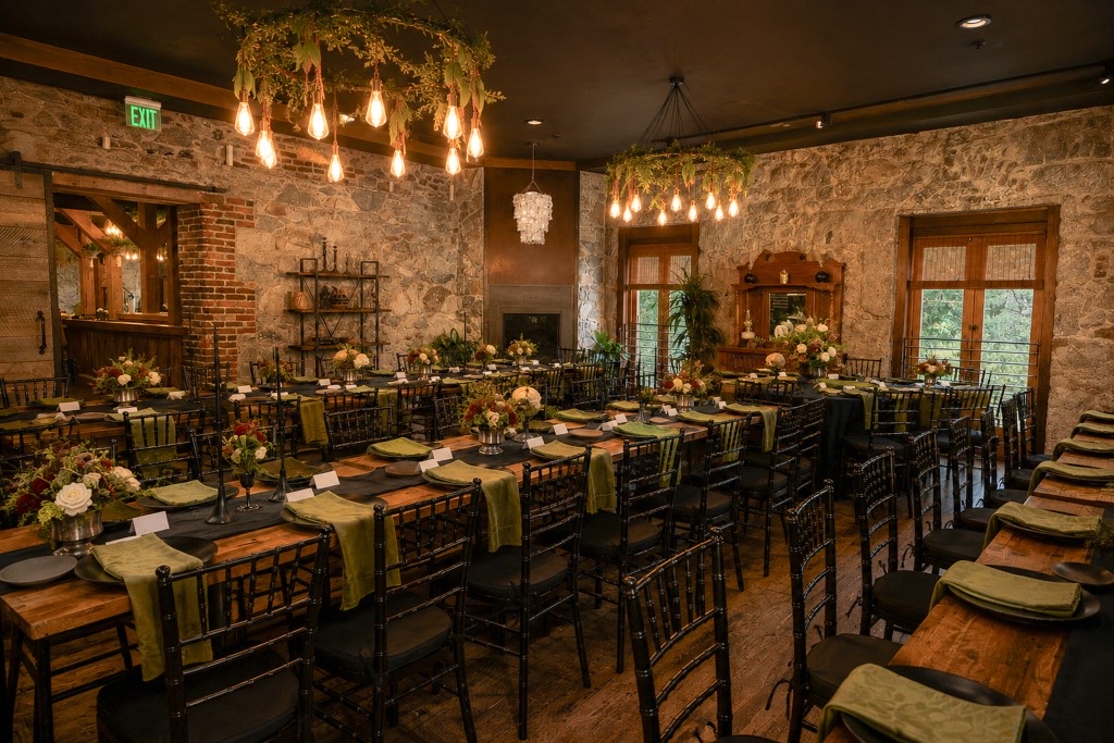 Dinner reception tables in The Lounge at Stone House Nevada City with stone walls and vine chandeliers